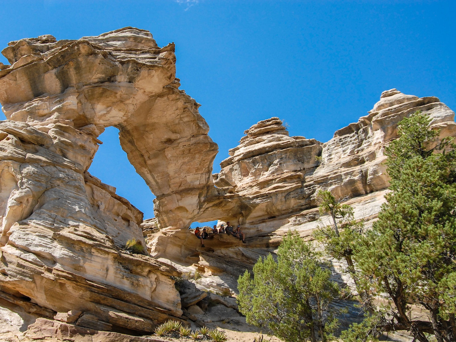 Personen sitzen unter großen Felsbogen in Utah