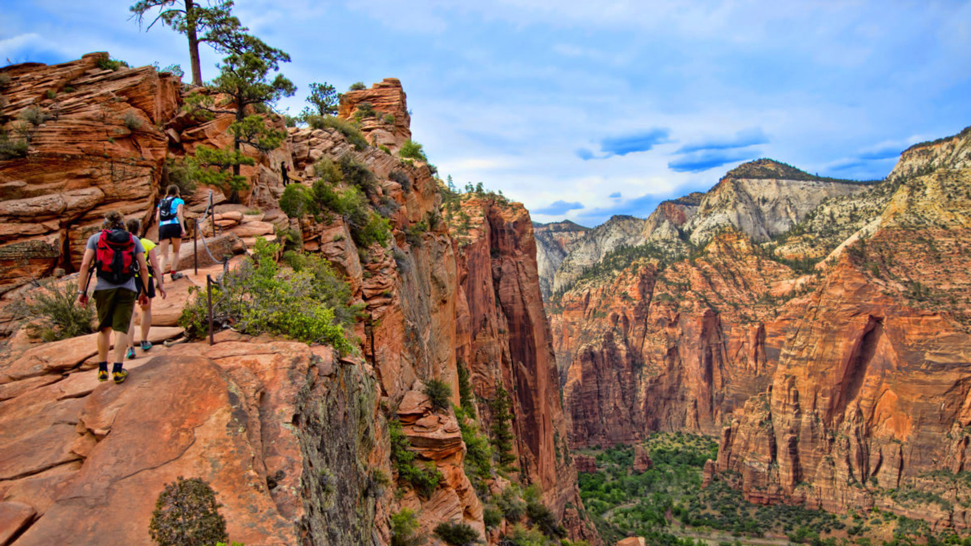 Personen wandern auf roter steiler Felswand neben Canyon in Utah