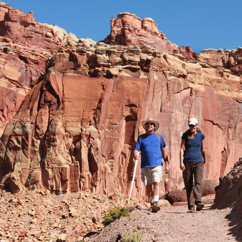 Zwei Menschen wandern durch die rote Felslandschaft im Capitol Reef Nationalpark in Utah, USA