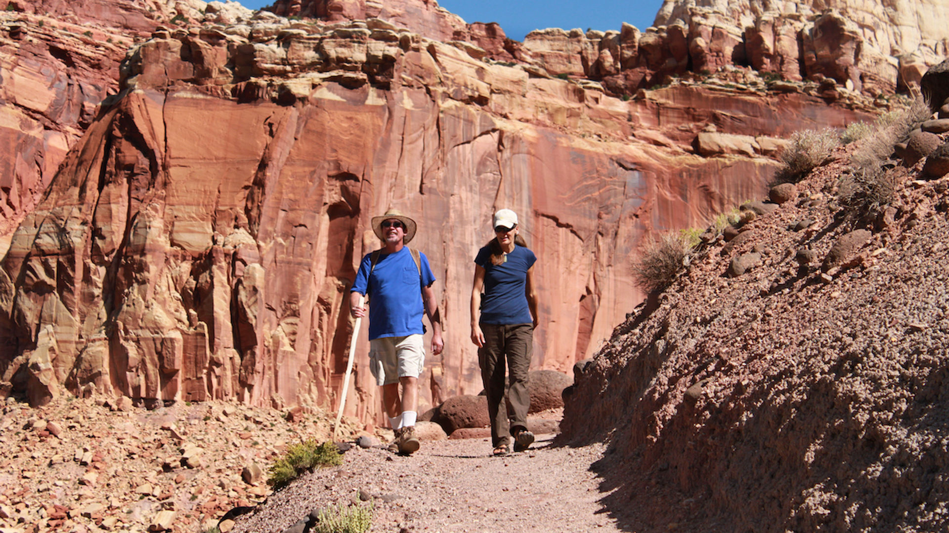 Zwei Menschen wandern durch die rote Felslandschaft im Capitol Reef Nationalpark in Utah, USA