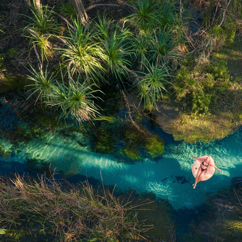 Eine Frau, die im Bitter Springs Elsey National Park auf einem Fluss treibt.