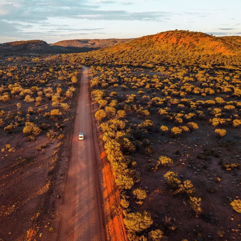 Ein Auto fährt auf einer geraden Straße im Red Centre in Australien.