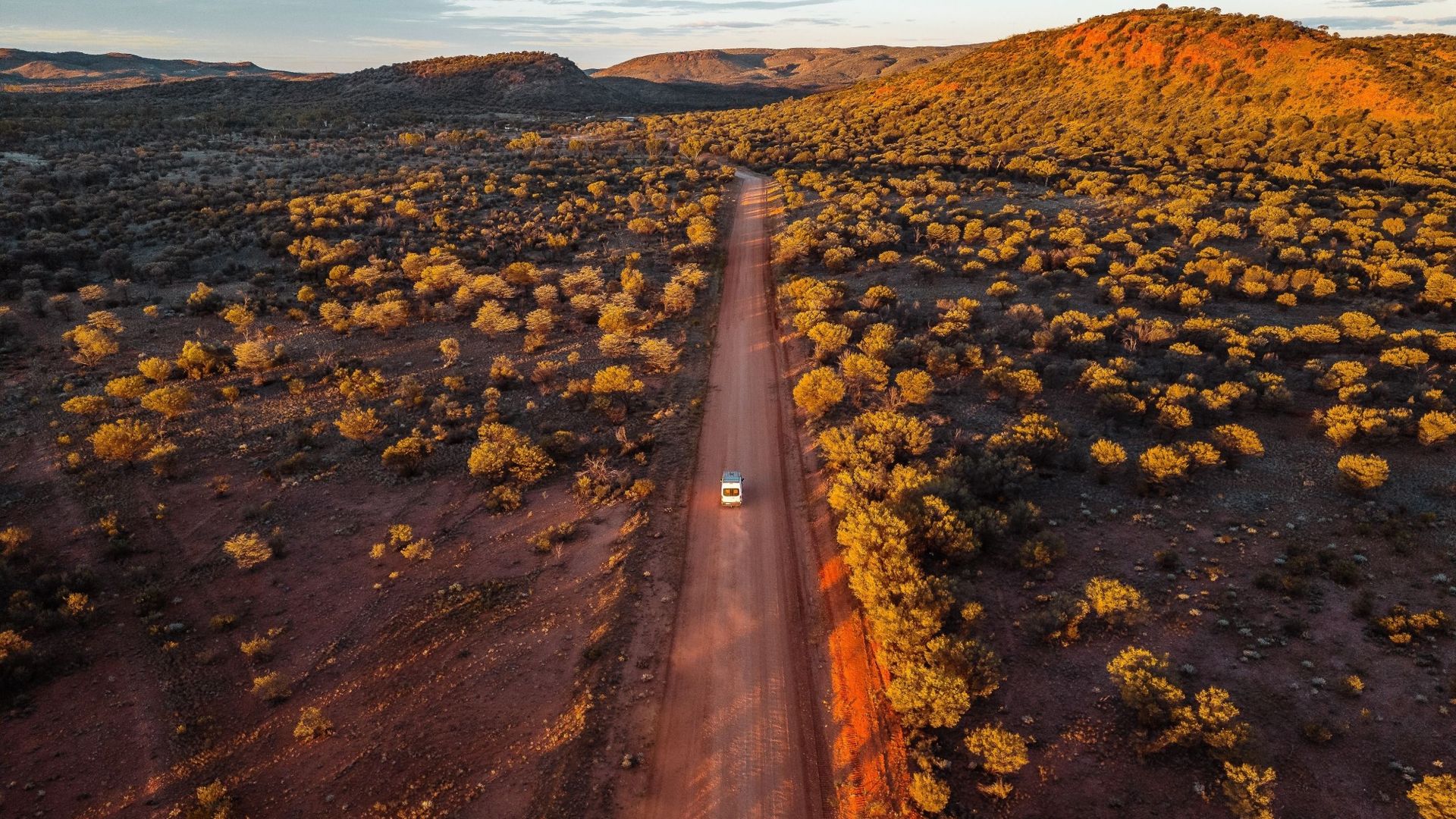 Ein Auto fährt auf einer geraden Straße im Red Centre in Australien.
