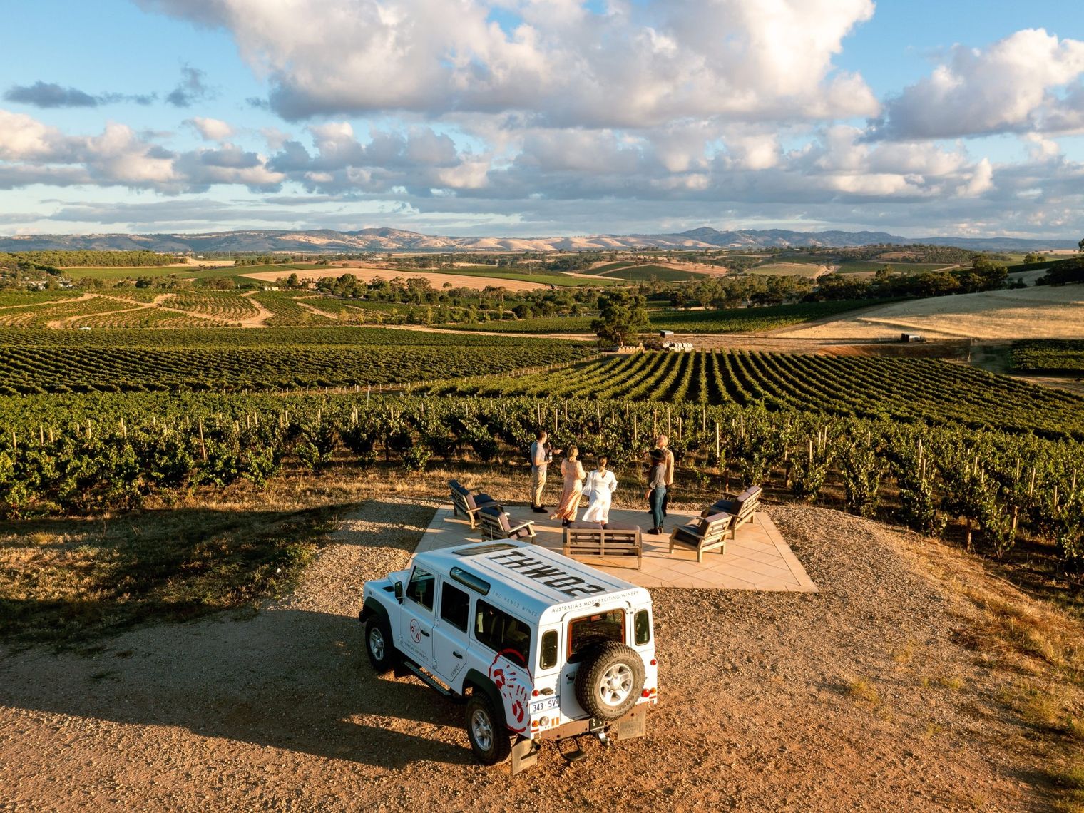 Menschen, die in einem Weinberg im Barossa Valley in Australien im Stehen etwas trinken.