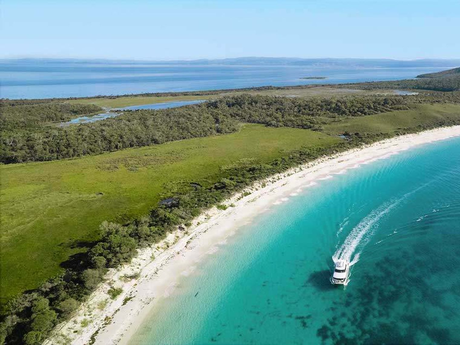 A boat moving across the coast of Wineglass bay in Australia
