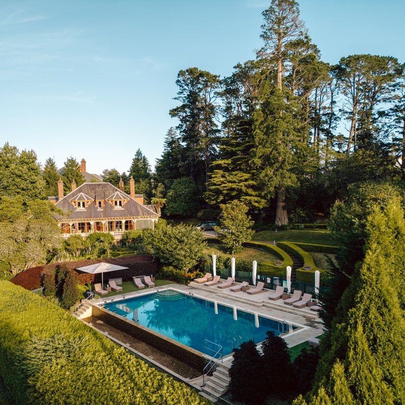 ein Boutique-Hotel und ein Swimmingpool mit Liegestühlen, umgeben von viel Grün