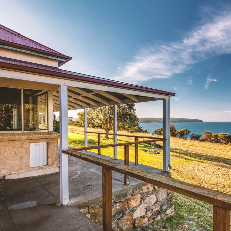 The terrace of a lodge with views over hills and the scenery and sea around Kangaroo Island