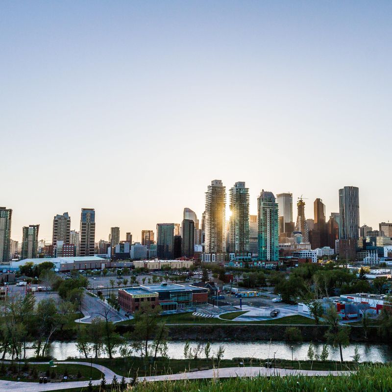 De skyline van Calgary met de ondergaande zon tussen de hoge gebouwen door