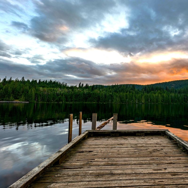 A small wooden pier juts out onto Powell River on Canada's Sunshine Coast, as the sun sets nearby