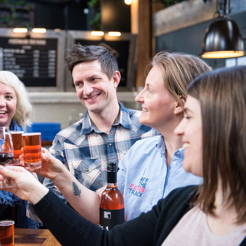 A group of people raise their glasses of wine and beer during a food tour in Victoria, British Columbia, Canada