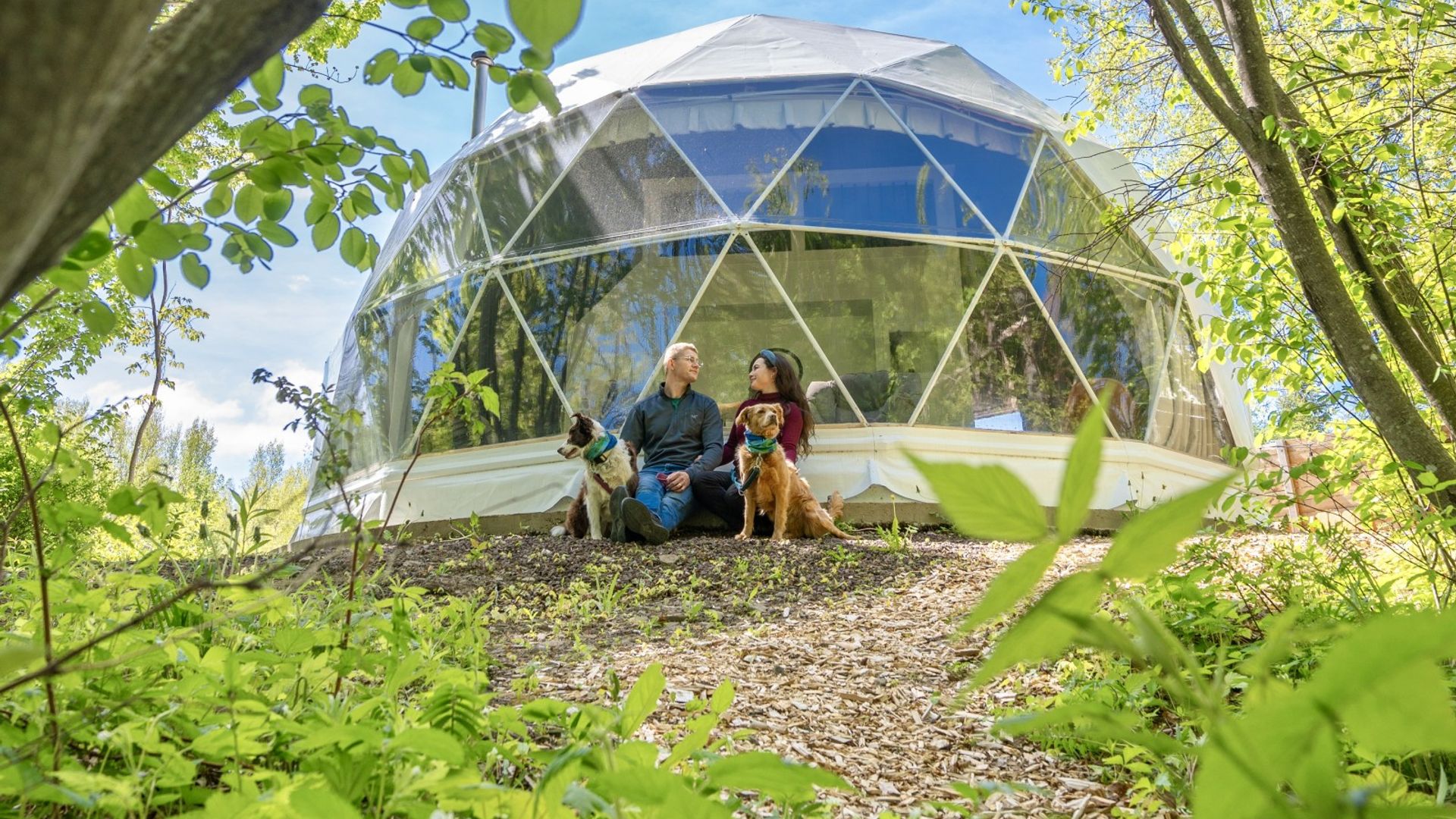 Paar mit Hund sitzt vor Glamping Dom in Kanada
