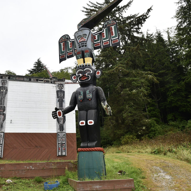 Een gebeeldhouwde en beschilderde inheemse totempaal en een traditioneel clanhuis met kunstwerken van de First Nations aan de Pacifische kust van British Columbia, Canada