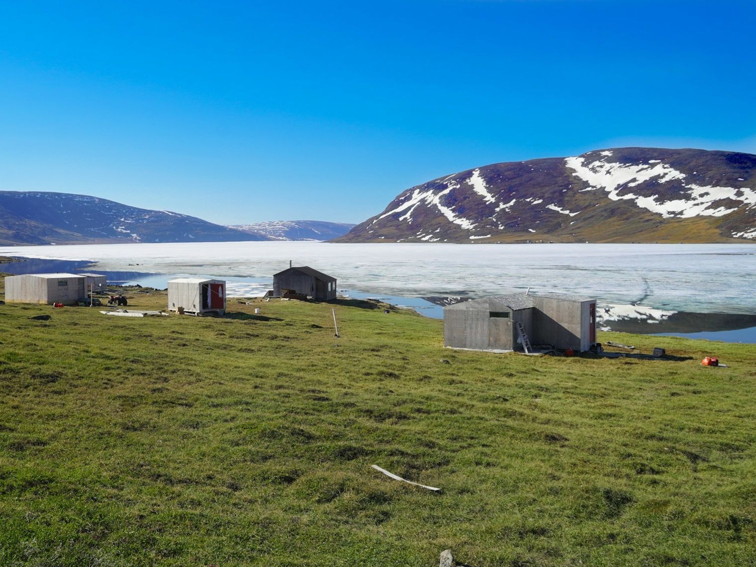 Eine Siedlung der Inuit auf einer weiten Wiese an einem zugefrorenen See