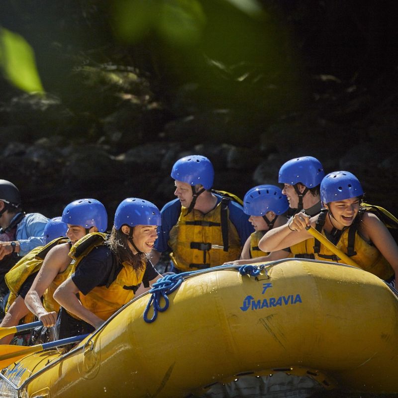 A group smile and laugh as they white water raft down the Madawaska River in Canada