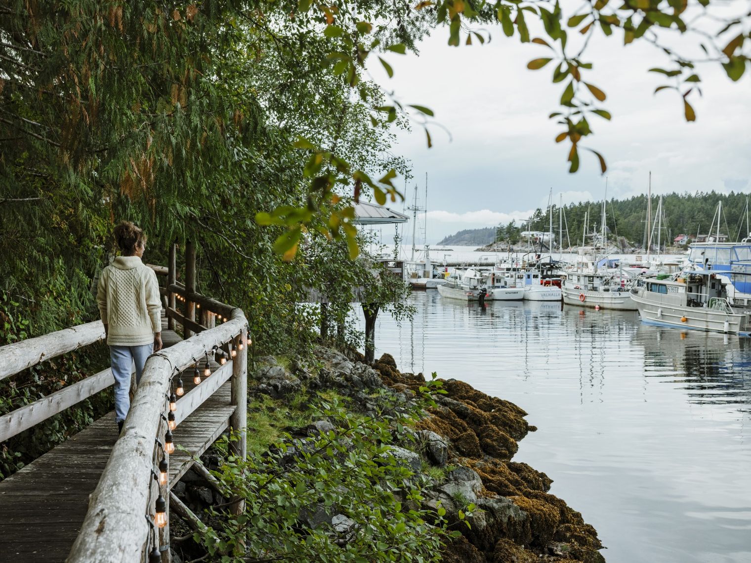 A woman walking along a bridged pathway in Sunshine Coast harbour