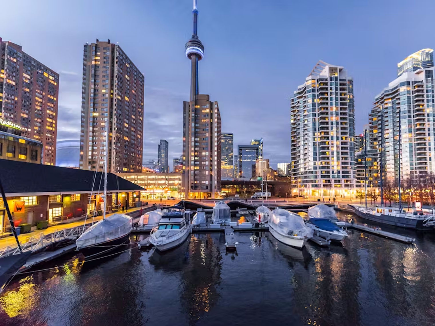 Boats moored up in Toronto Harbour at night with a background of the city skyline