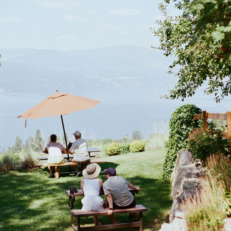 Menschen, die draußen sitzen und bei einem Glas Wein den Blick auf den See und die Berge genießen.