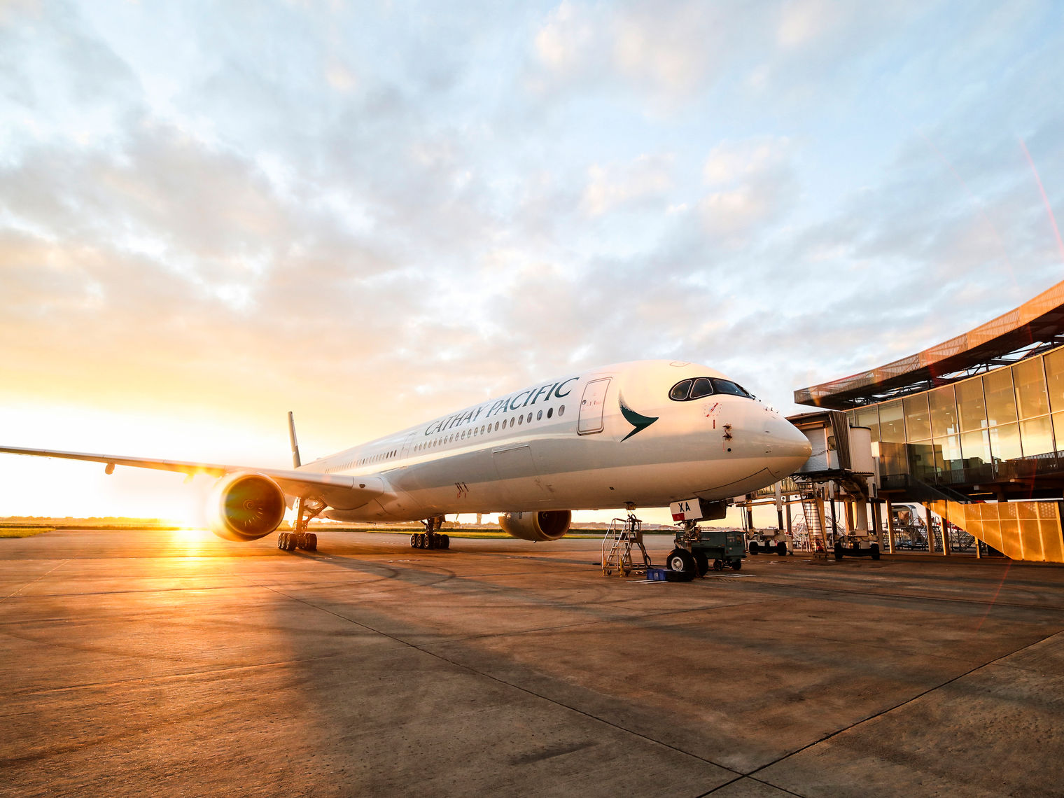 Een Cathay Pacific Airbus op het vliegveld met een zonsondergang op de achtergrond.