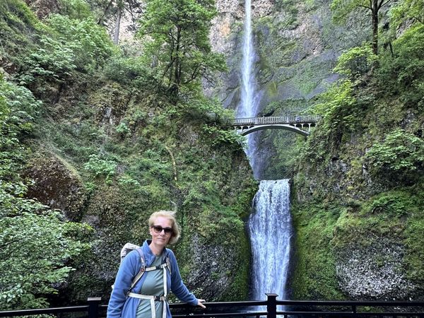 Ellen tegen een weelderig groene, rotsachtige achtergrond met een brug die over de waterval loopt
