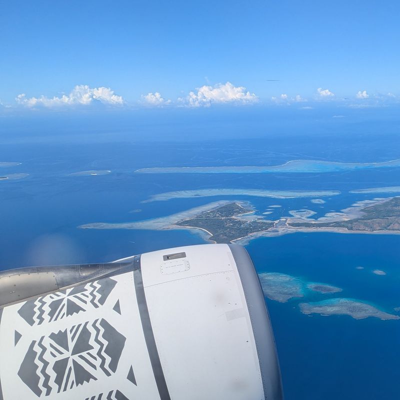 Blick aus dem Fenster eines Flugzeugs der Fiji Airways, das die fidschianischen Inseln überfliegt