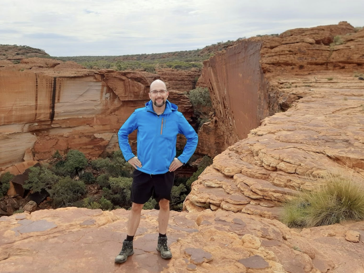 Mann mit blauer Jacke steht vor roter Felsenschlucht in Australien