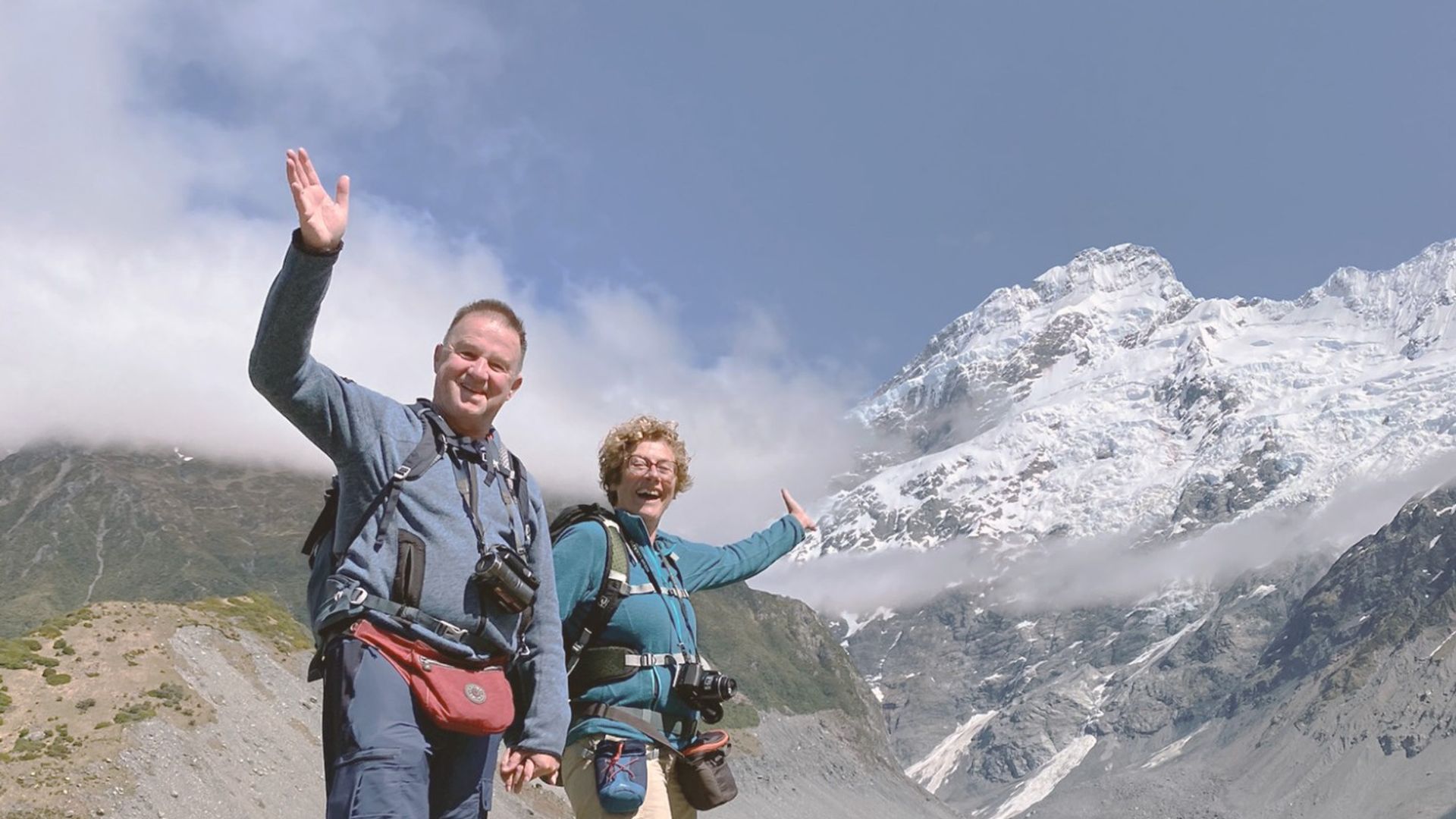 Wandelaars poseren tegen de achtergrond van de met sneeuw bedekte Mount Cook, die hoog boven een gletsjerlandschap uittorent langs de Hooker Valley Track in Nieuw-Zeeland