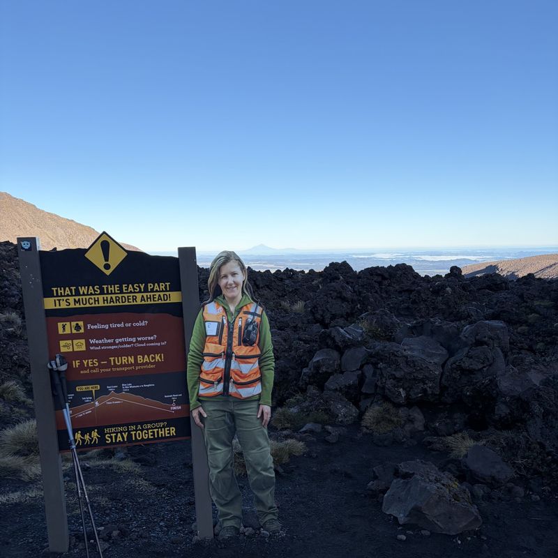 Wandelgids bij een waarschuwingsbord op de Tongariro Alpine Crossing, Nieuw-Zeeland