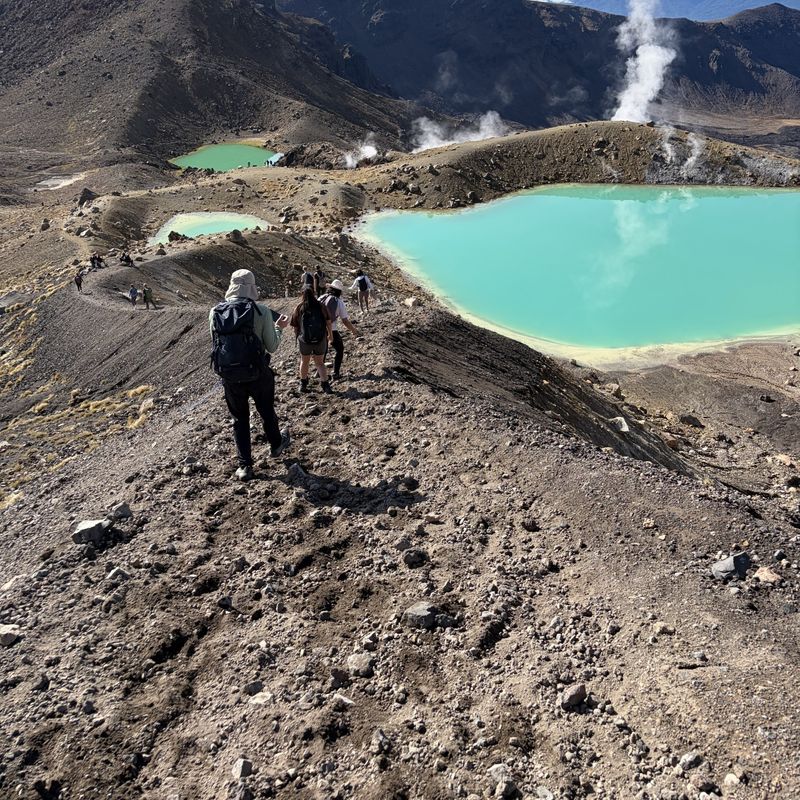Wandelaars dalen af richting de Emerald Lakes op de Tongariro Alpine Crossing, Nieuw-Zeeland