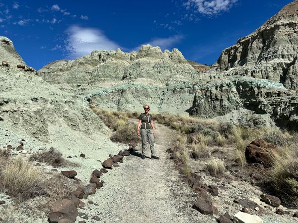 Een vrouw die het John Day Fossil National Monument bezoekt en poseert naast de Sheep Rock Unit.