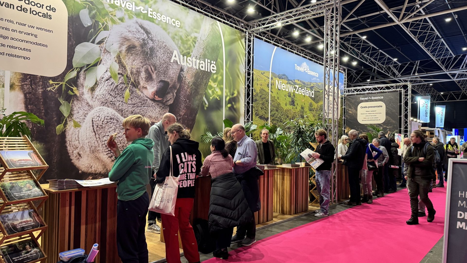 Bezoekers bekijken brochures bij de TravelEssence-stand tijdens een reisbeurs