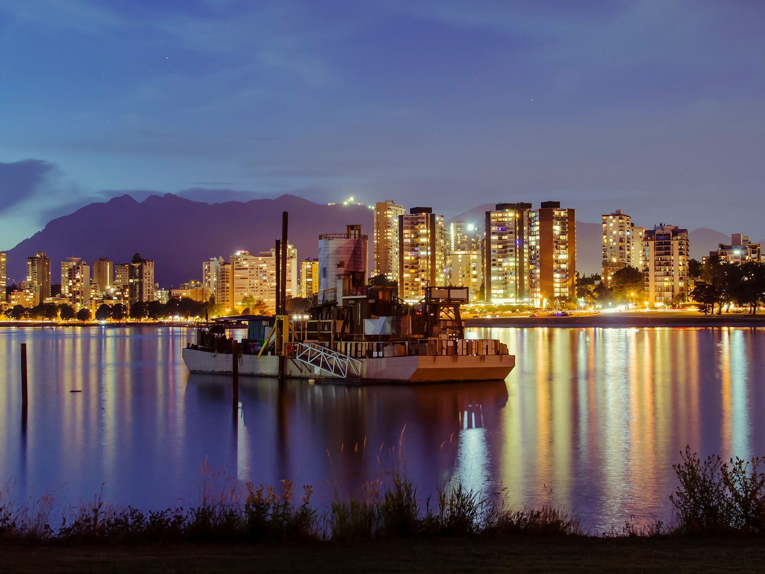 Beleuchtete Skyline von Vancouver, Kanada, in der Abenddämmerung mit ruhigem Wasser