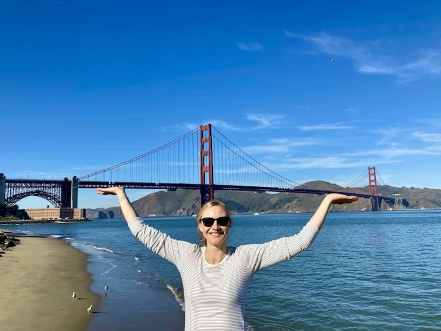 Blonde Frau steht vor Golden Gate Bridge in San Francisco und gibt vor sie zu halten