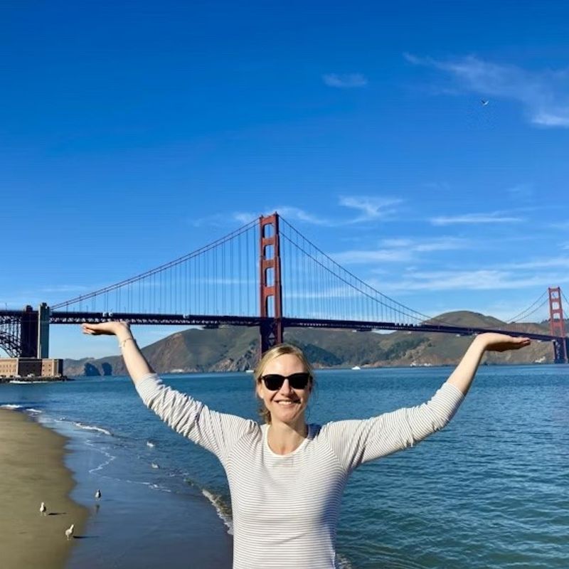 Blonde Frau steht vor Golden Gate Bridge in San Francisco und gibt vor sie zu halten