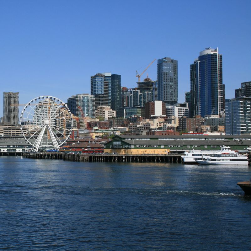 De skyline van Seattle, Washington met het water en een reuzenrad op de voorgrond
