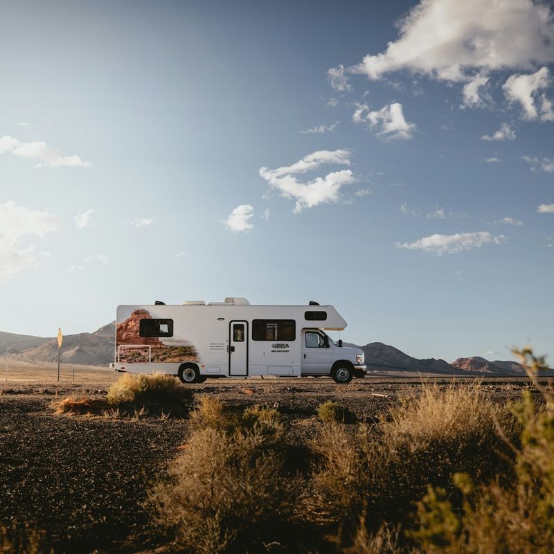 Camper in wüstenartiger Landschaft mit Hügeln im Hintergrund