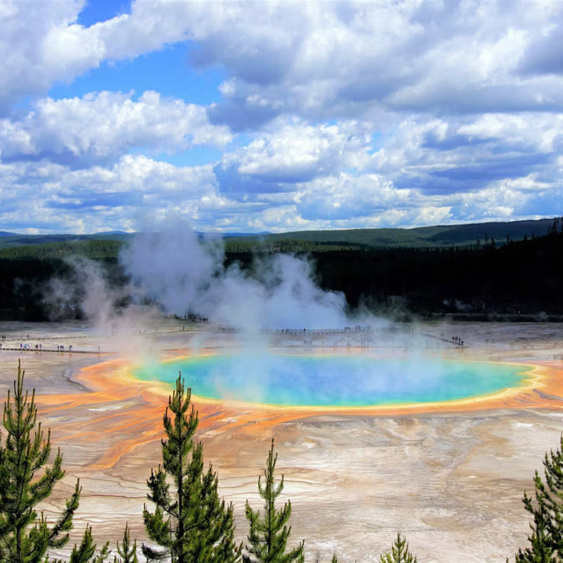 Old Faithful Geyser steaming in Yellowstone National Park with colours of blue, green, orange and yellow
