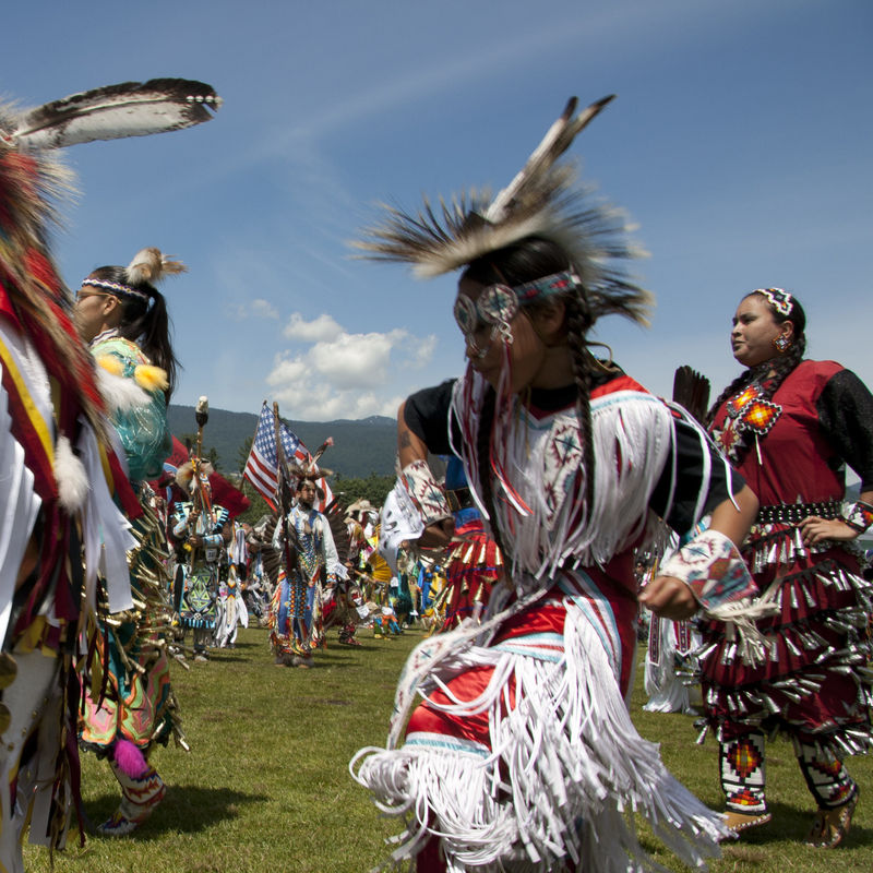 Een dansende groep First Nations, dragen traditionele kleding en hoofddeksels
