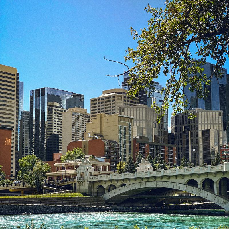 Uitzicht op een rivier in Calgary met een brug en wolkenkrabbers op een zonnige dag