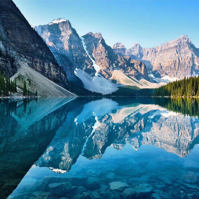 View over a lake, the forest meets the mountains range in the background