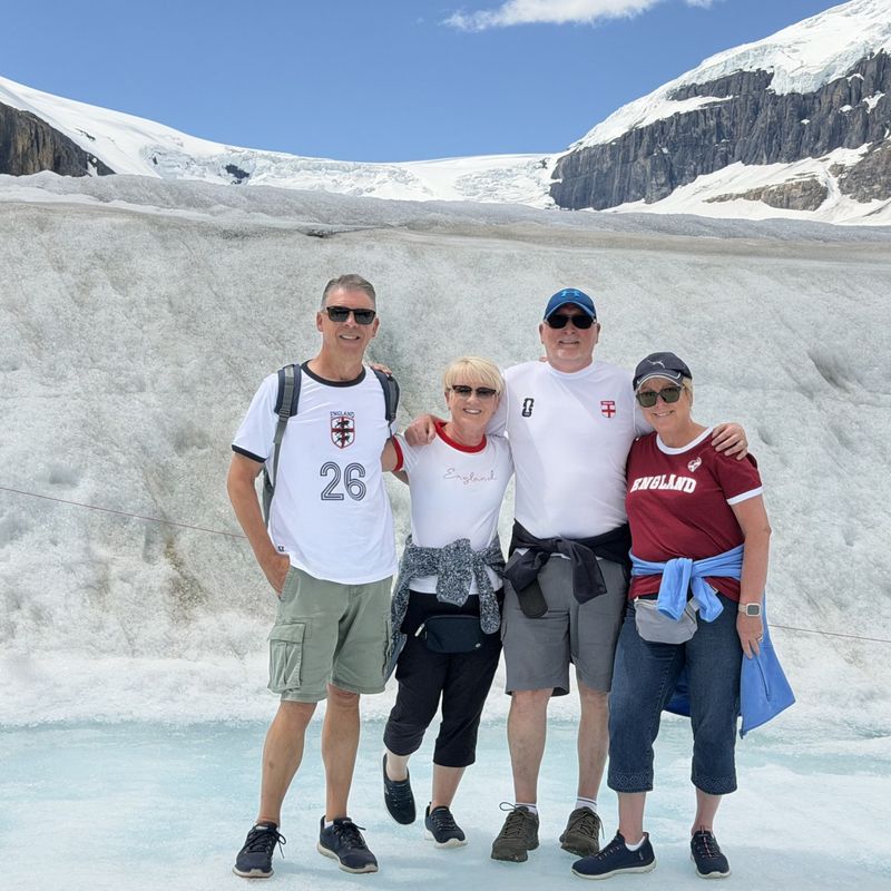 Four friends standing for a photo in front of the Athabasca Glacier