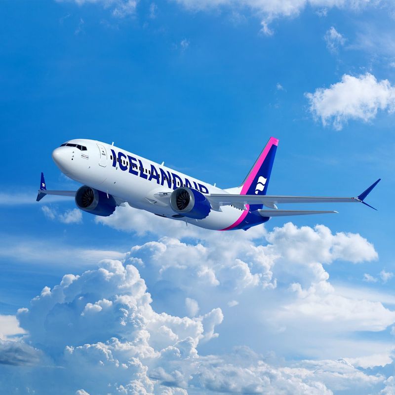 Een vliegtuig van Icelandair vliegt boven helderwitte wolken tegen een strakblauwe lucht.