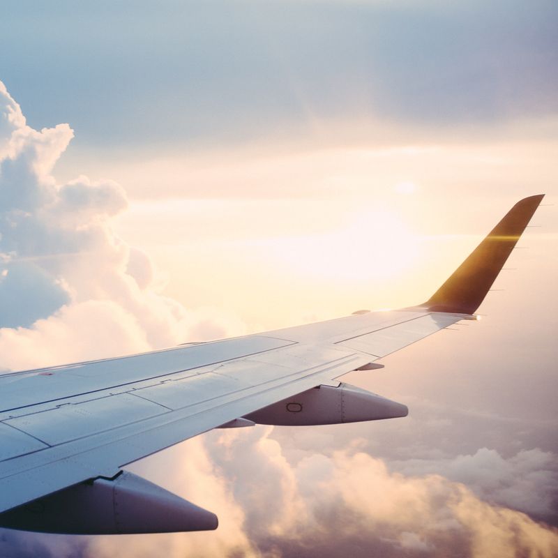 Blick auf Flugzeugflügel in den Wolken mit Sonne