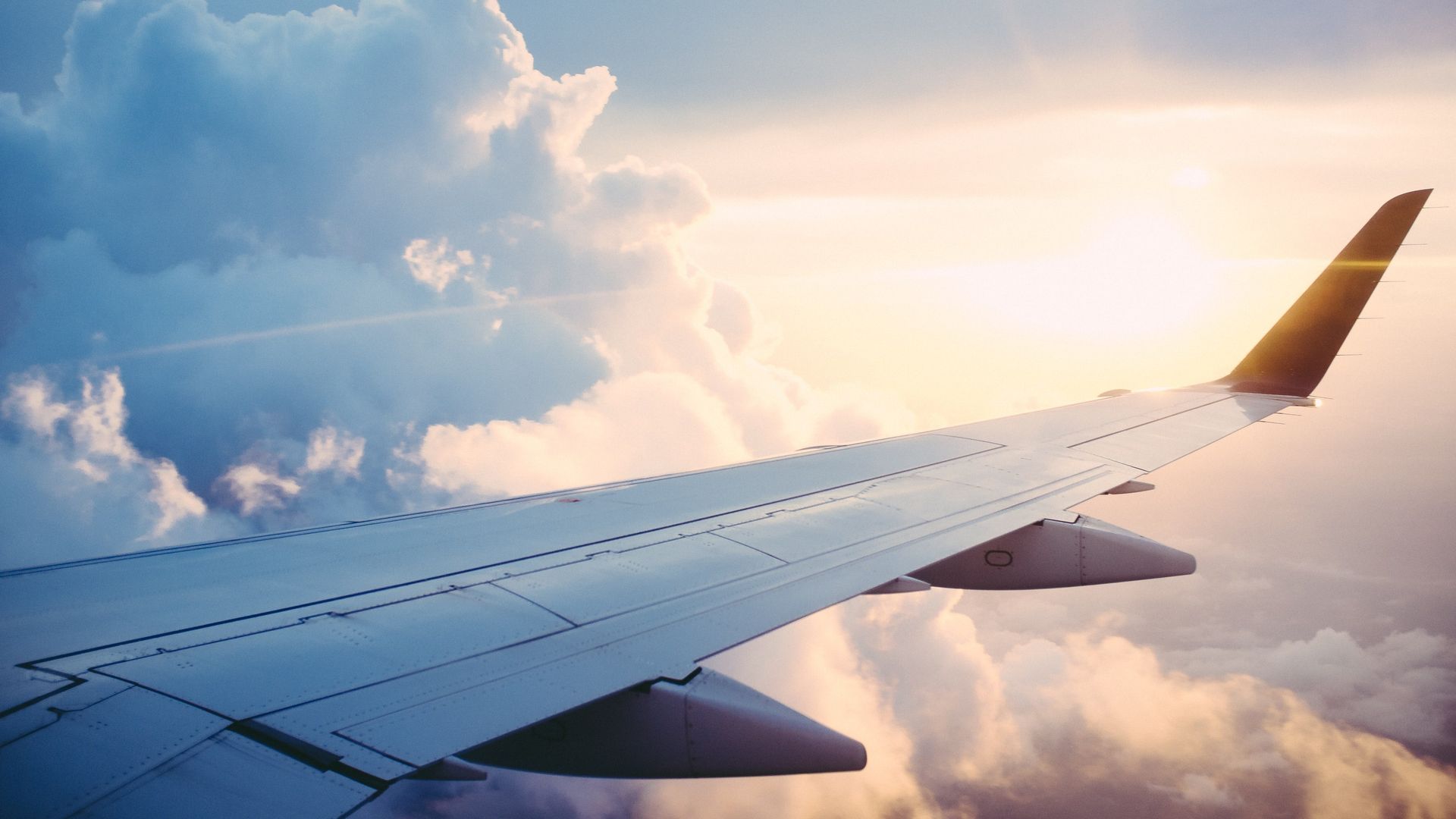 Blick auf Flugzeugflügel in den Wolken mit Sonne