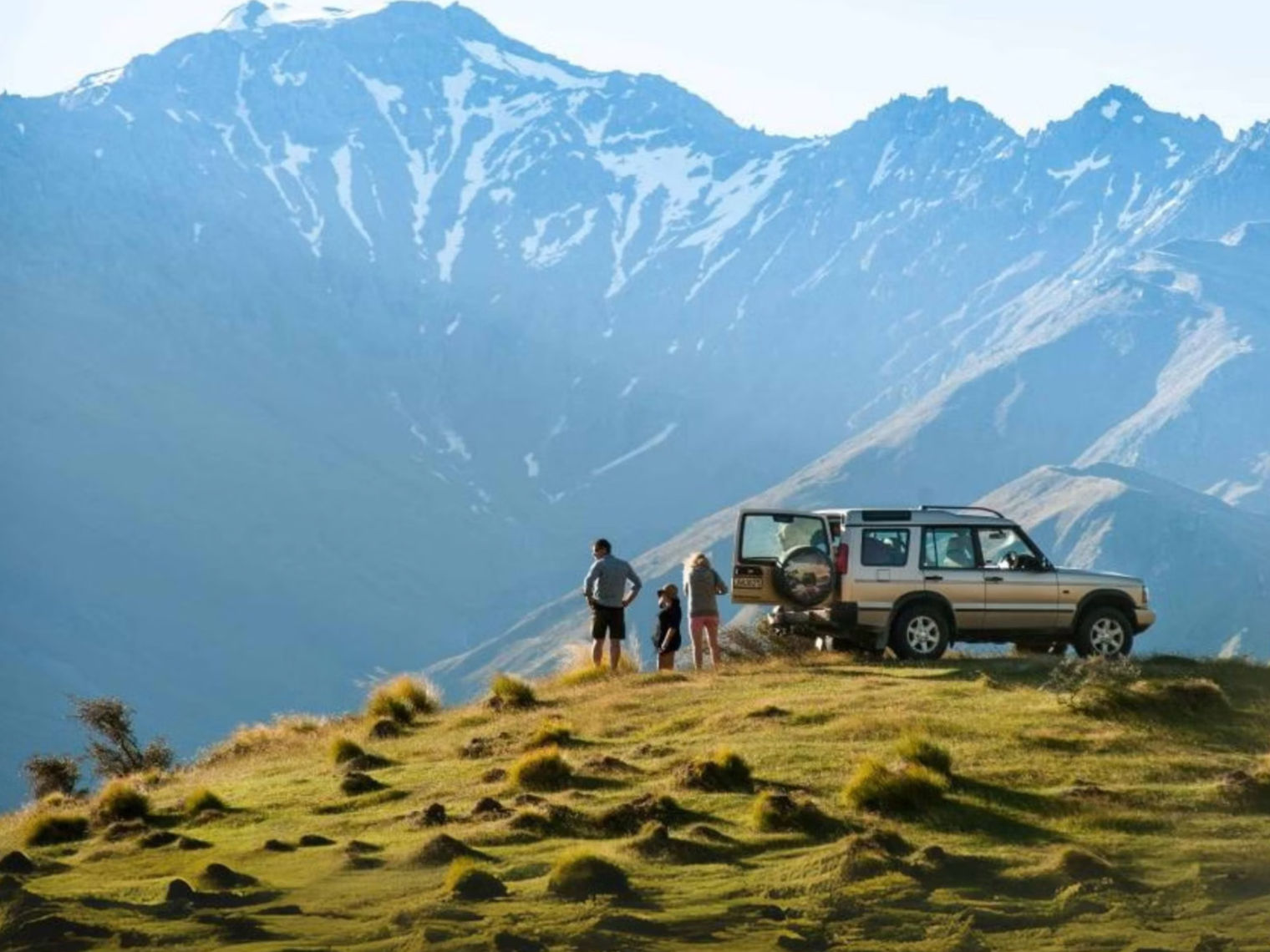 Menschen, die aus einem Auto aussteigen und auf schneebedeckte Berge blicken