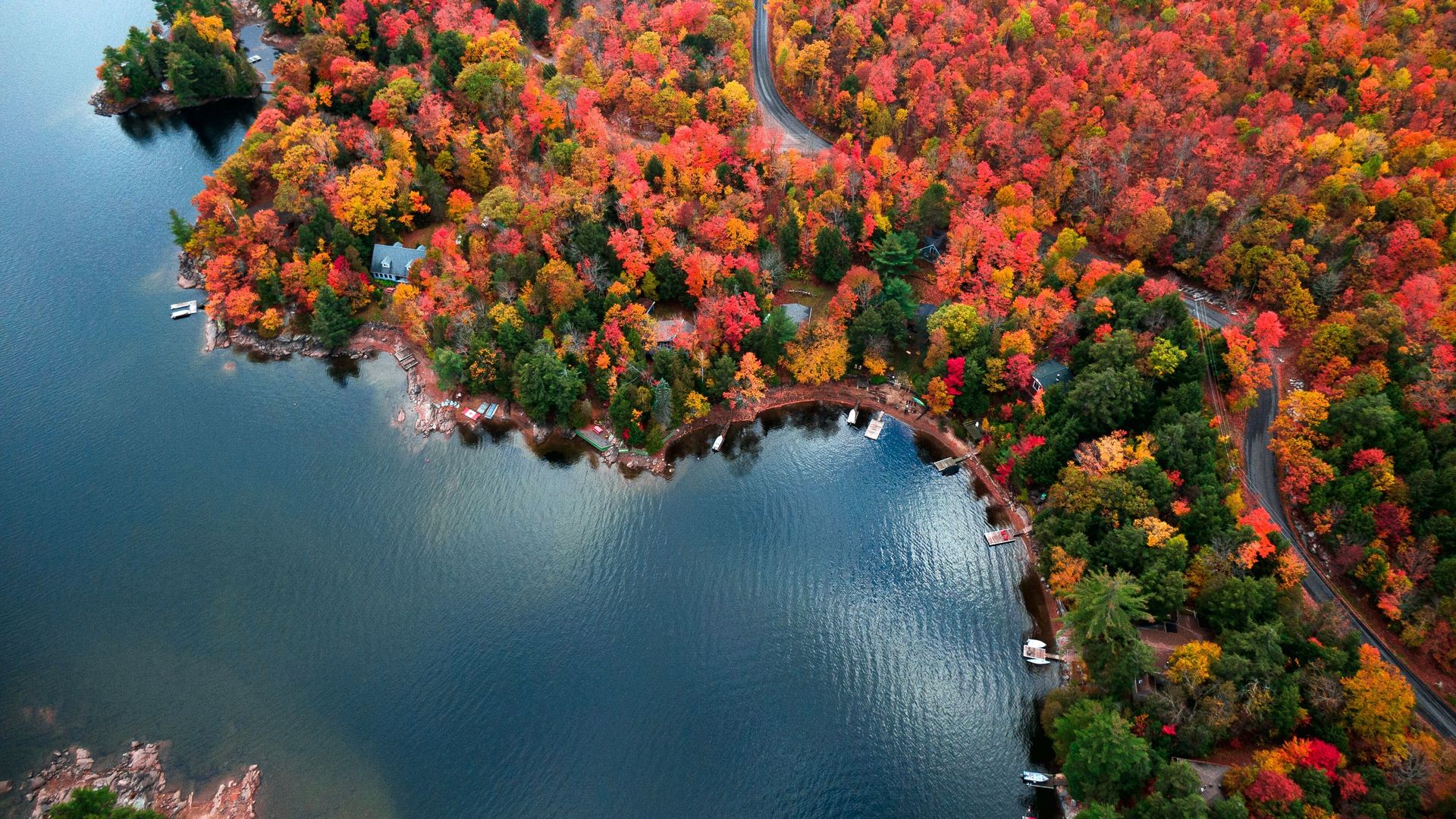 Luftaufnahme eines Sees in Kanada, umgeben von einem leuchtend bunten Herbstwald