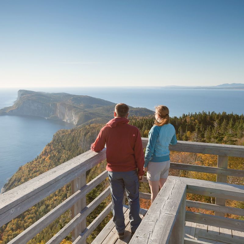 Twee personen staan op een ballustrade in Forillon National Park, Quebec, genietend van het uitzicht op zee en de kaap..