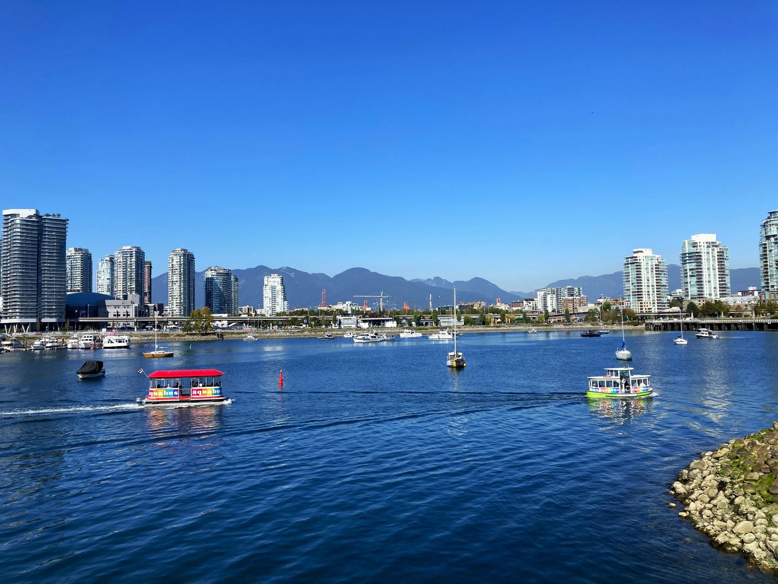 Bunter Aquabus fährt über das Wasser mit Skyline von Vancouver und Berge im Hintergrund