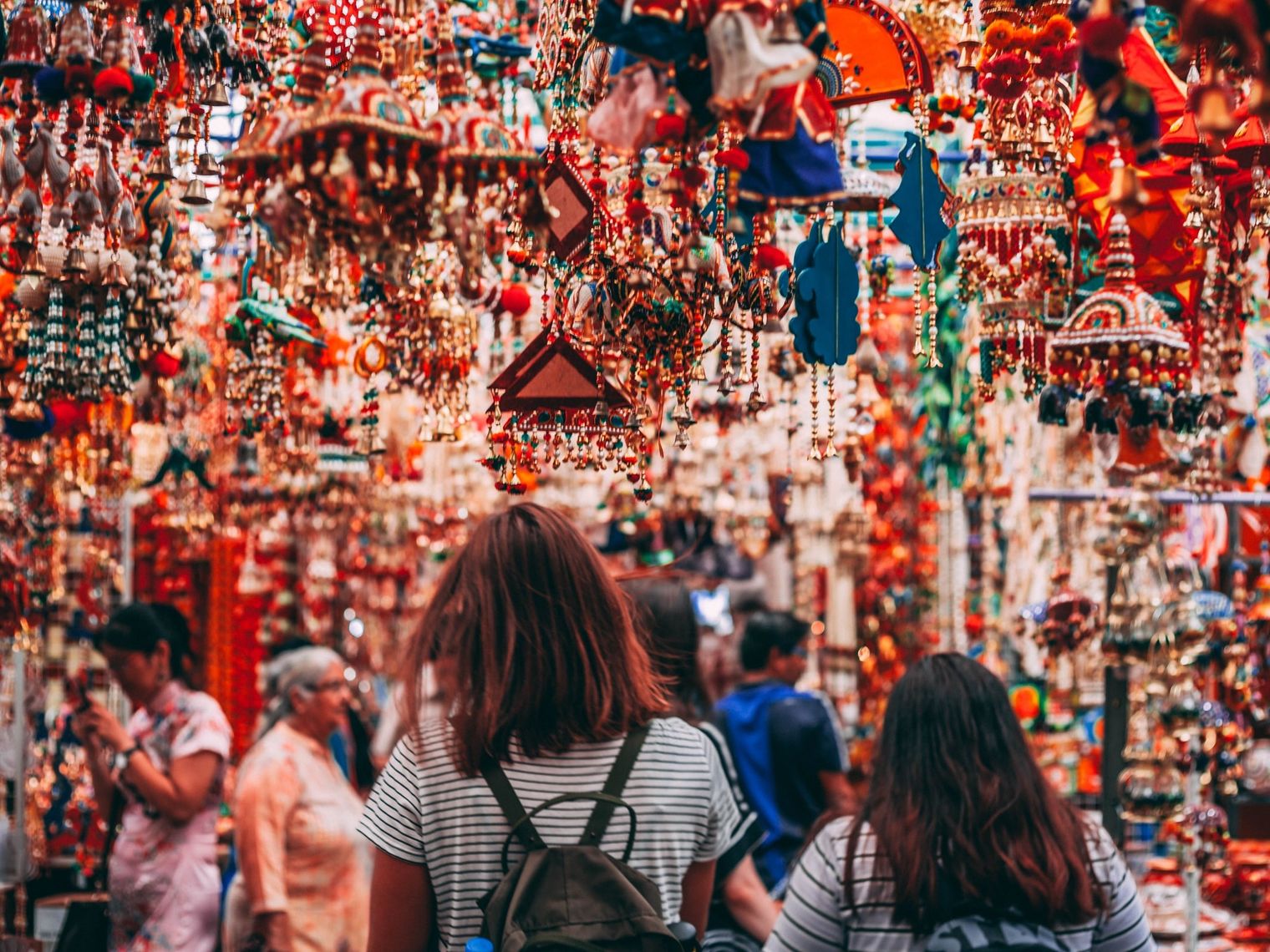 Zwei Frauen von hinten auf einem bunten Markt in Singapur