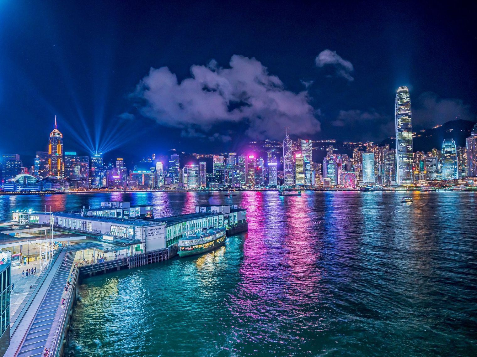 Zicht op de helder verlichte stad 's nachts, kleuren weerspiegelen in het water in Hong-Kong