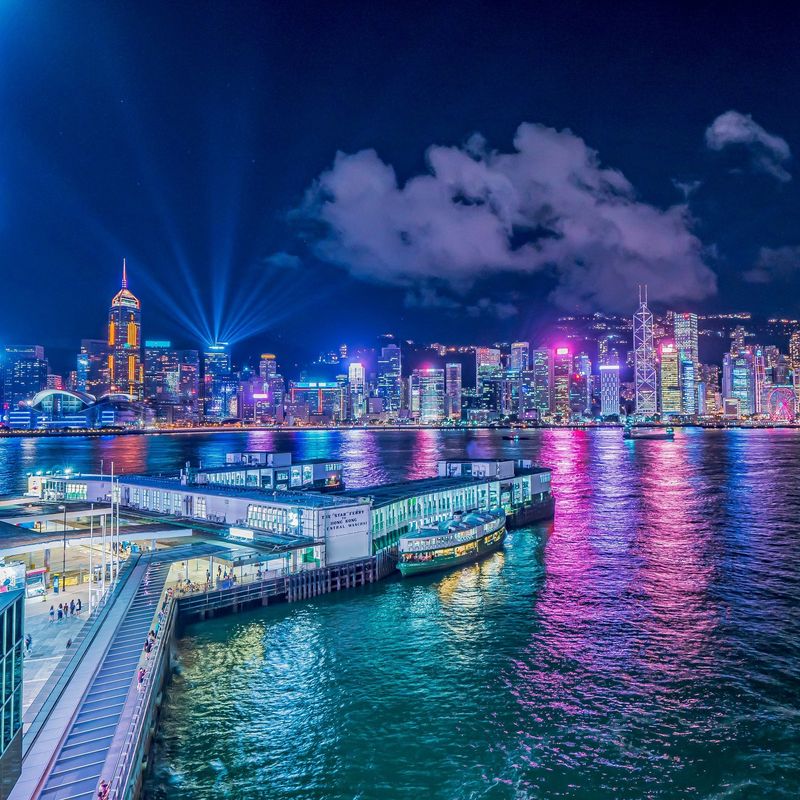 View of the city brightly lit up at night, colours reflecting in water in Hong-Kong